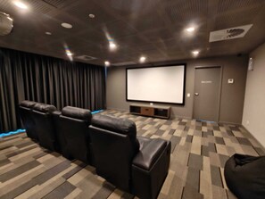 A home theater room with a large screen, leather recliner seating, and a carpeted floor. - Apartment in Adelaide CBD with parking (Adelaide)