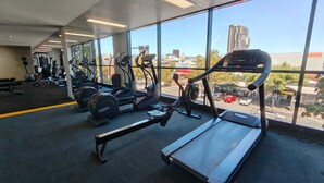Une salle de sport équipée de tapis de course, de vélos elliptiques et de bancs de musculation.