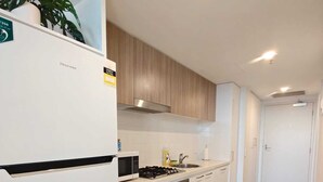 Une cuisine moderne avec des armoires blanches, un four encastré et une hotte de cuisine en acier inoxydable.