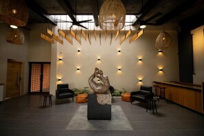 A lobby with a central sculpture, seating area, and a reception desk. - Hotel Aeropuerto Ángel Albino Corzo (Chiapa de Corzo)