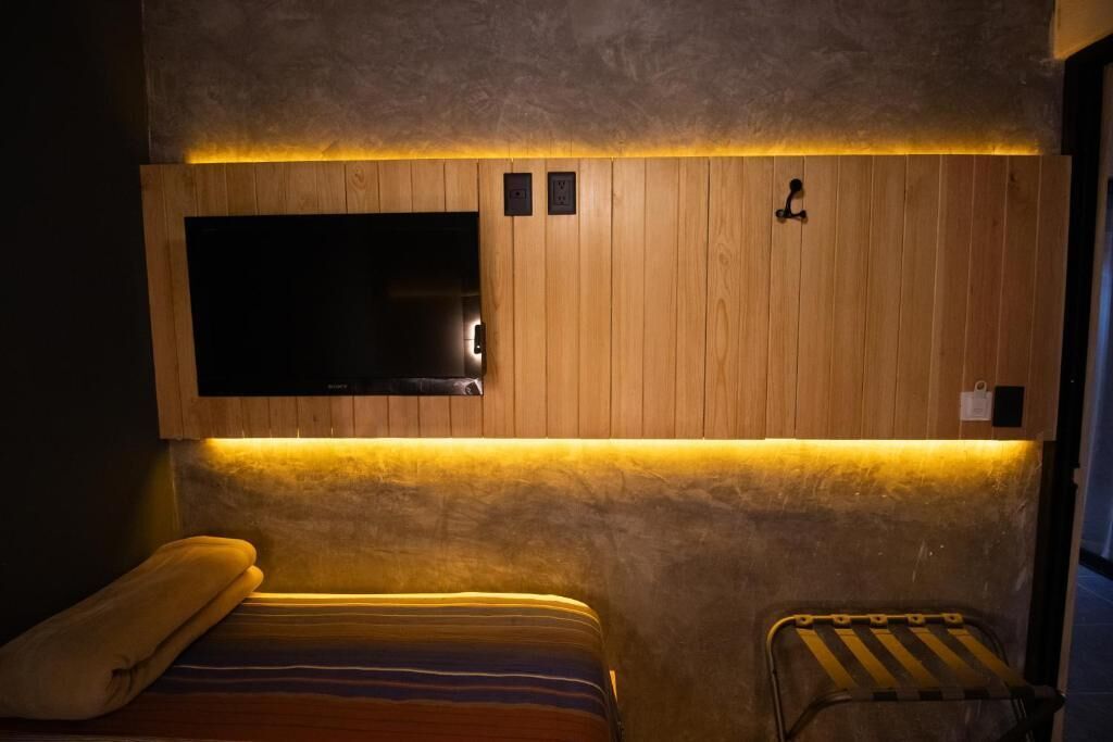 Een kamer met een bed, een zithoekje, een aan de muur bevestigde televisie en een houten paneelwand.