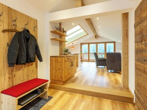 Ein Zimmer mit einer Holzbänkl, einem Kleiderständer, einem Holzschrank und einem Stuhl.