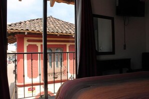 A hotel room with a balcony, a bed, a TV, and a window with curtains. - hotel avenida  (Zacatlán)