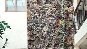 A stone wall with a water feature, potted plants, and a metal fence. - hotel avenida  (Zacatlán)