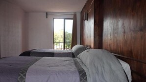 A room with two beds, a wooden wall, and a window with a view. - hotel avenida  (Zacatlán)