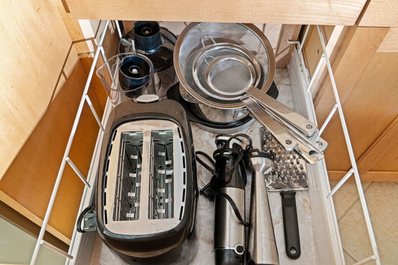 A kitchen with a toaster, a grater, a strainer, and a kettle.