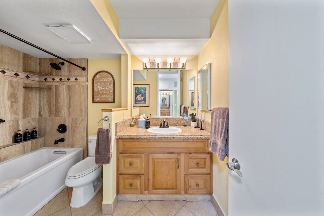 A bathroom with a bathtub, toilet, vanity with a sink, and wooden cabinets.