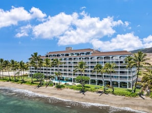 A multi-story hotel with balconies, a pool, and palm trees. - Maui Beachfront Haven – Unit 433 (Lahaina)