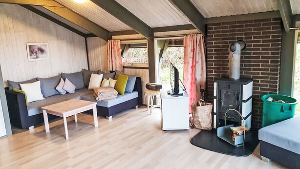 Een gezellige kamer met een bank, een tafel, een open haard en een raam met gordijnen.