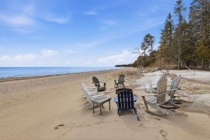 Ein Strand mit Holz-Adirondack-Stühlen, die halbkreisförmig angeordnet sind und auf den Ozean blicken.