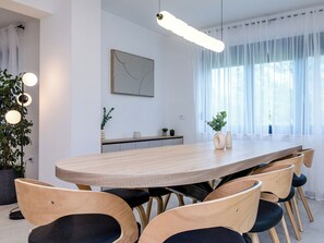 A modern dining area with a long wooden table, matching chairs, and pendant lighting. - Vacation home Antica by Interhome (Rab/Lopar)