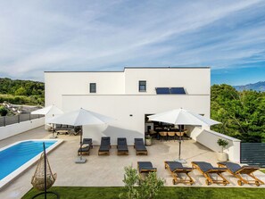 A modern building with a pool, sun loungers, and umbrellas. - Vacation home Antica by Interhome (Rab/Lopar)