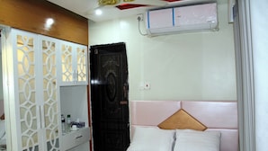 A bedroom with a bed, a wardrobe, a door, and an air conditioning unit. - Hotel Safari International Patuakhali (Patuakhali Sadar)
