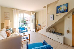 Ein Wohnzimmer mit einer Couch, einem Sessel, einem Couchtisch, einer Treppe und einem Gemälde an der Wand.