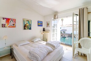 Ein Schlafzimmer mit einem Bett, einem Glastisch, einer Lampe und Bildern an den Wänden.