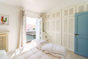 Ein Schlafzimmer mit einem Bett, einem weißen Heizkörper, einem Balkon mit einem Stuhl und einer Tür mit Lamellen.