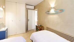 A bedroom with two beds, a wardrobe, a dresser, a wall-mounted light, and a beach-themed sign. - PORT GRIMAUD: Superb 3-room apartment - A/C, terrace and garden (PORT GRIMAUD)