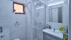 A modern bathroom with a glass shower enclosure, a window with flowers, a sink with a mirror, and a toilet. - Adorable 1-bedroom bed & breakfast in lively Nairobi (Nairobi)