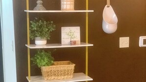 A wall-mounted shelf unit with various decorative items including a potted plant, a framed picture, and a wicker basket.