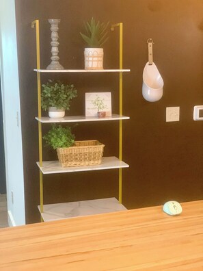 A wall-mounted shelf unit with various decorative items including a potted plant, a framed picture, and a wicker basket.