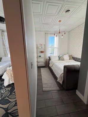 Ein Schlafzimmer mit einem Bett, einem Nachttisch, einer Kommode und einem Fenster mit Vorhängen.