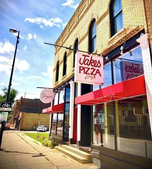 A pizza restaurant with a sign reading 'Takes Pizza' and a 'Bike Lane' sign nearby.