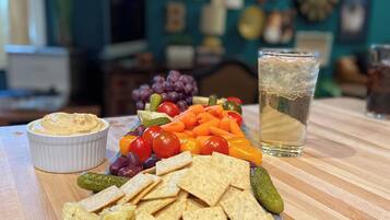 A snack platter with crackers, cheese, and vegetables on a wooden table.