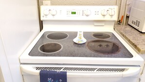 A white stove with four burners, a digital display, and a control panel with various settings. - Furnished 2BR - Ideal for Relocation & Extended Stays (Fort Lauderdale)