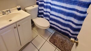 A bathroom with a white sink, toilet, and shower curtain. - Furnished 2BR - Ideal for Relocation & Extended Stays (Fort Lauderdale)