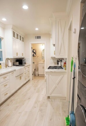 A modern kitchen with white cabinetry, a central island, and a built-in stove. - 3B2B Luxury Riverside Retreat - Near UCR, CUS, Downtown, Historic Park & More (Riverside)