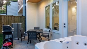 An outdoor patio with a hot tub, a grill, and a table with chairs. - 10 Mins to NRG, Sleeps 12, Hot Tub, 4BR Home (Houston)
