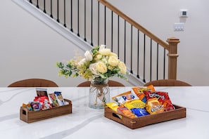 A table with a vase of flowers, two wooden gift boxes, and a white wall with a staircase in the background.