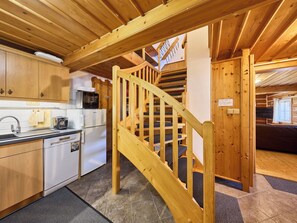 A wooden interior with a kitchen, a staircase, and a living area.