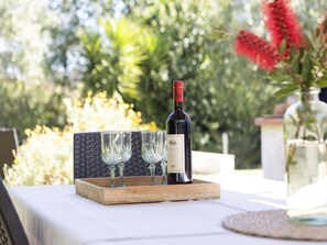 A bottle of wine on a tray with glasses, set outdoors with greenery in the background. - The Baby Suite, modern and refined (Portoferraio)