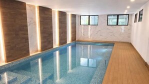 A swimming pool with wooden flooring, marble walls, and ceiling lights. - Edificio Arles (Guatemala City)