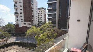 A balcony with a glass railing, two wicker chairs, and a small table. - Edificio Arles (Guatemala City)