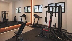 A modern gym with exercise equipment, a large mirror, and windows. - Edificio Arles (Guatemala City)