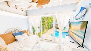 Ein Schlafzimmer mit Bett, Fernseher, Deckenventilator und Blick auf einen Swimmingpool.