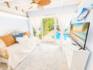 Ein Schlafzimmer mit Bett, Fernseher, Deckenventilator und Blick auf einen Swimmingpool.