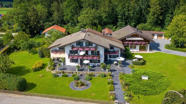 Ein großes Gebäude mit einem zentralen Innenhof, umgeben von üppiger Vegetation und einem bewaldeten Hintergrund.