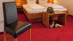 A hotel room with a bed, a chair, a bedside table with a lamp, and a pair of shoes on the floor. - New four-star vacation apartment with 53 sqm No. 5, Die Moderne (Gstadt am Chiemsee)