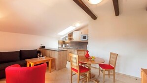 A compact living space with a kitchenette, a dining area with a table and chairs, and a sofa. - New four-star vacation apartment with 53 sqm No. 5, Die Moderne (Gstadt am Chiemsee)