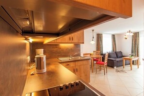 Eine moderne Küche mit Holzschränken, einem Einbauherd und einer Kaffeemaschine.