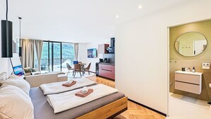 Ein modernes Hotelzimmer mit einem großen Bett, einer Essecke, einer Küche und einem Badezimmer.