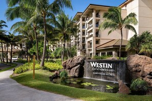 Ein Westin Vacation Club Gebäude mit Schild, Palmen, Wasserspiel und gepflastertem Weg.