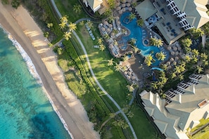 Luftaufnahme eines Resorts mit Strand, großem Poolbereich und mehreren Gebäuden.