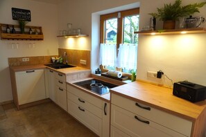 Une cuisine équipée d’un évier, d’une cuisinière, de meubles de rangement en bois et d’une fenêtre avec des rideaux.