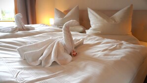 A hotel room with a bed, pillows, and a towel arranged in a swan shape. - Vacation apartment "Wendelsteinblick" (Heufeld)