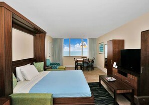 Ein Hotelzimmer mit Bett, Fernseher, Schreibtisch und Blick auf den Himmel.