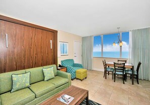Ein Wohnzimmer mit Sofa, Hocker, Esstisch, Stühlen und Meerblick.